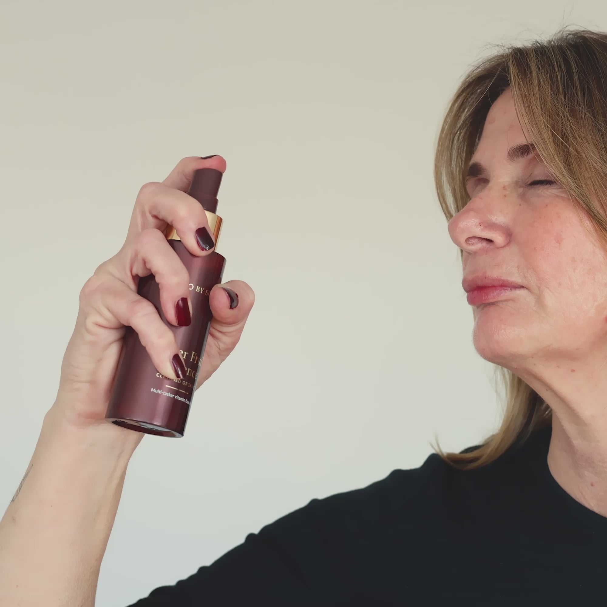 Woman spraying Super Fruit Essence onto her face.